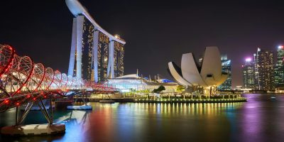 Stunning night view of Marina Bay Sands and Helix Bridge illuminated over water in Singapore.